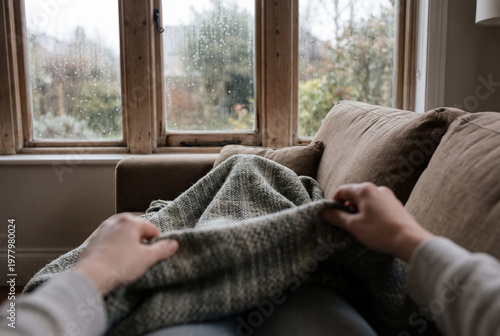 Woman's hands pulling cozy blanket on sofa at home