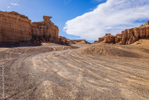 Sandy road winding through rugged canyon rock formations in Xinjiang, China
