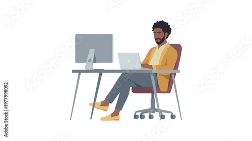 A professional African American man works attentively on a laptop at a desk with a desktop computer