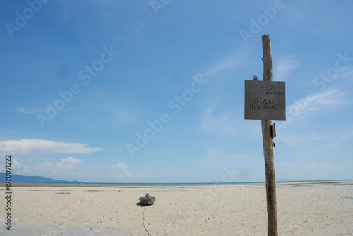 Foto Abandoned Boat Moored on Empty Beach with Warning Sign