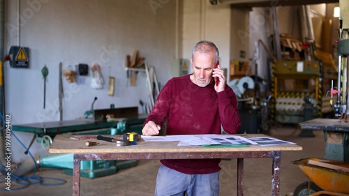 Bild auf Leinwand Senior woodworker managing small business with phone call