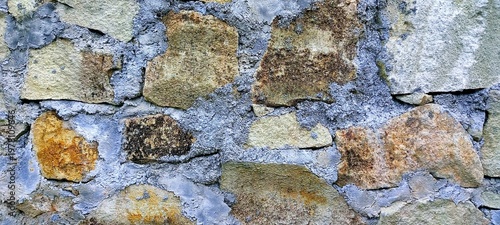 Close-up of a rustic stone wall with rough textures and earthy tones, creating a vintage natural background ideal for wallpaper, adding depth, character, and timeless architectural charm.