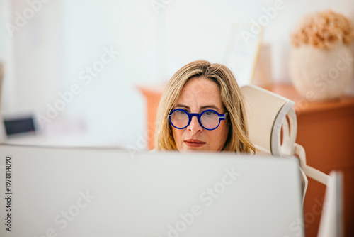 Professional woman wearing blue glasses concentrating at work