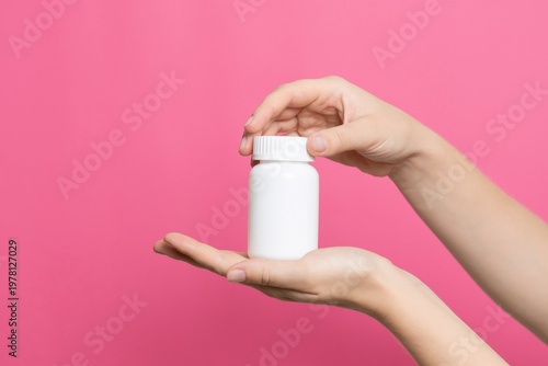 Hands holding white medicine bottle with cap