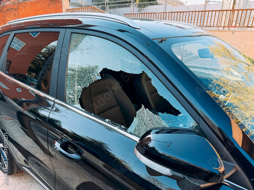 Broken car side window with shattered glass edges.