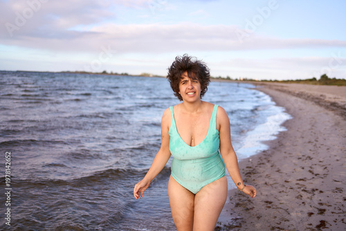 plus size woman in a turquoise swimsuit splashing in the sea on a Copenhagen beach
