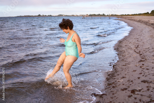  midsize woman in a turquoise swimsuit enjoying a bright life at the Copenhagen seaside