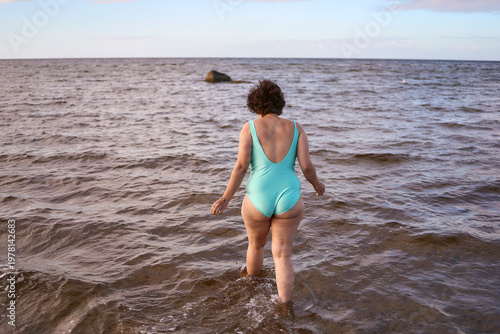  midsize woman in a turquoise swimsuit enjoying a bright life at the Copenhagen seaside