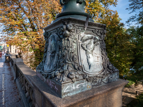 Ornate bronze base of a candelabra lamp post on the Legion Bridge in Prague, Czech Republic,
