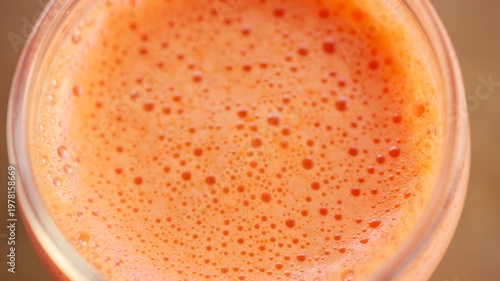 Extreme close up of fresh orange juice surface with bubbles and foam texture