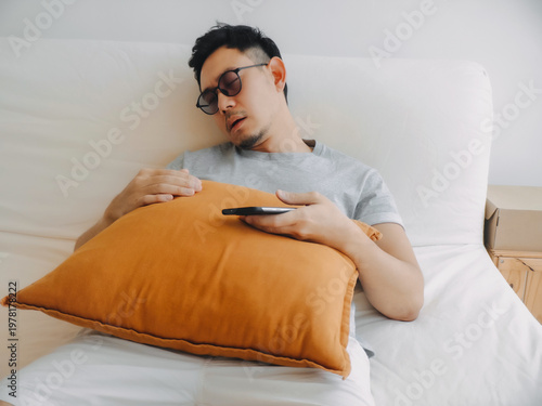 Comfortable relaxed posture of asian man resting with pillow and phone