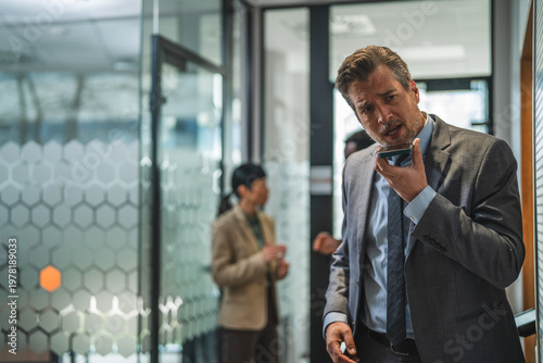 Foto Businessman recording audio message on smart phone in office