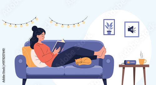 Woman relaxes on a blue sofa while reading a book with her sleeping cat and a warm cup of coffee on a table nearby.