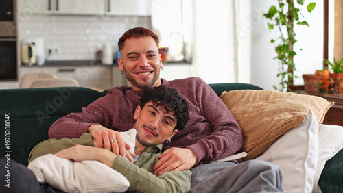 Happy gay couple relaxing on sofa at home