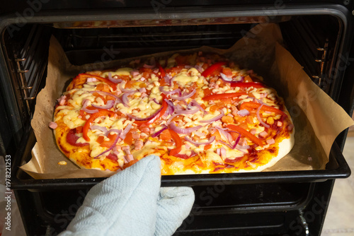Homemade Pizza with Vegetables and Ham Baking in Oven on Parchment