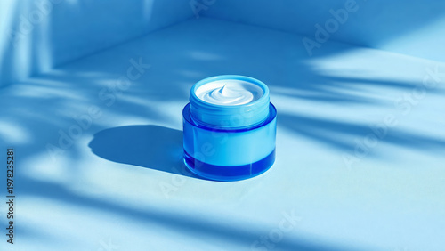 Blue cream jar opened on minimal blue surface with shadows
