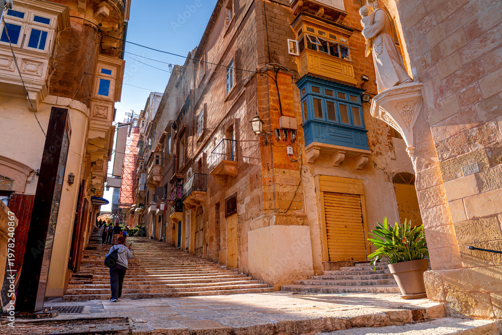 Fototapeta premium Traditional Maltese street with people walking, Valetta.