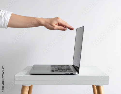 Hand opening laptop on white table