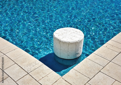 White stone stool in a bright blue swimming pool corner.