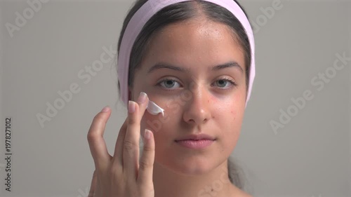 Young woman applying facial moisturizer cream on natural face skincare routine beauty treatment close up