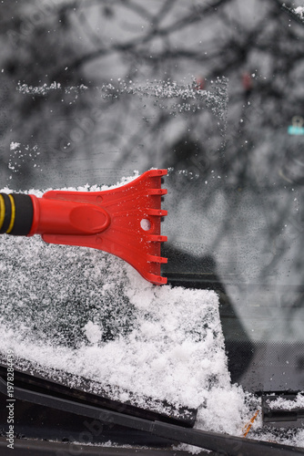 Red Ice Scraper Cleaning Car Windshield From Snow And Frost In Winter Close Up
