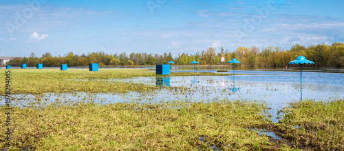 Flooded Beach Landscape With Blue Umbrellas And Cabanas During Spring River Flood