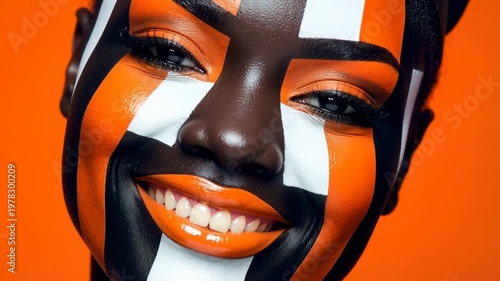 In a studio filled with bright colors, a person shows off bold face painting. Joy and creativity shine in each frame as they smile and express happiness through art.