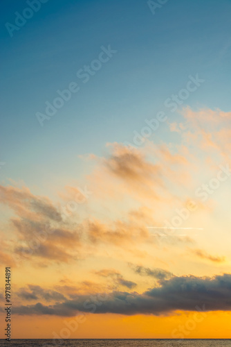 changing weather forecast. air pressure. scenic cloudscape. golden clouds on the blue morning sky over sea horizon. idyllic sunrise vertical background. fantastic golden hour wallpaper at the sea
