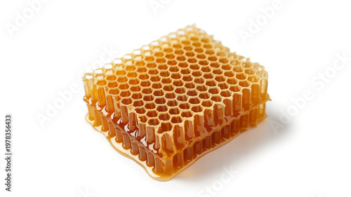 A closeup macro of natural golden honeycomb with sweet honey isolated on a white background showing yellow hexagonal wax cells and healthy organic beeswax