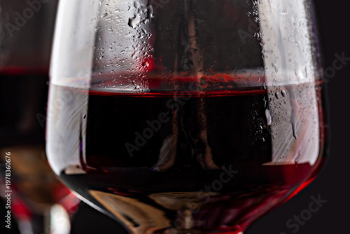 Grapes wine. Close-up view of glass filled with red wine, highlighting its deep color and clarity, with condensation visible on surface, set against dark background for contrast