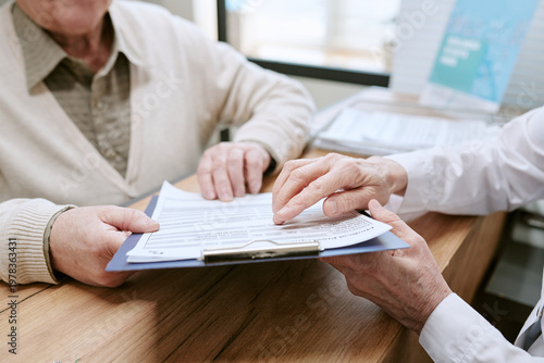 Foto Senior patient reviewing medical form with healthcare professional, discussing treatment details during clinic consultation