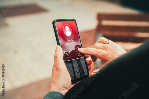 Scam call warning on smartphone screen declined by mature woman. Suspicious call concept.