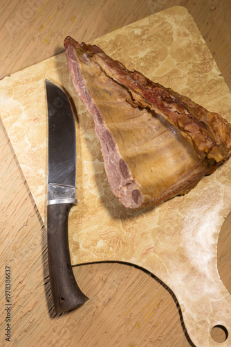 Professional cutting board with textured surface, knife, and fresh meat piece. Wooden base emphasizes natural quality and culinary preparation. 
