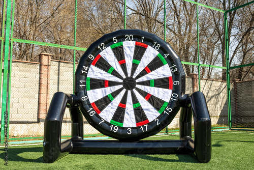 Inflatable dartboard on artificial turf in sports area.