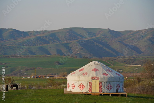 Kazakh national yurt on a green field against a background of hills. Traditions, the Nauryz spring festival. Country life.