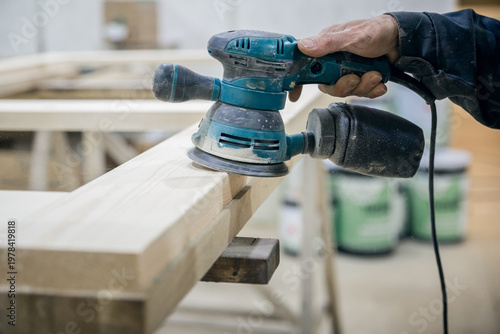 Tableau sur toile Worker sanding the wooden surface. In the hand of the power tool.