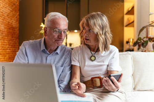 Фотография Senior couple calculating retirement finances with laptop and smartphone