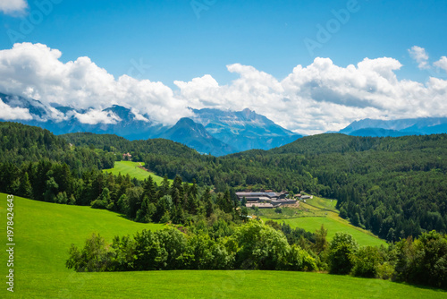A breathtaking alpine landscape with green meadows, pine forests and majestic mountain peaks on background near Bolzano, South Tyrol province, Italy.