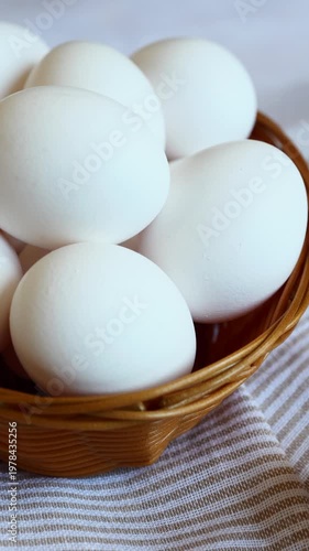 Freshly gathered white eggs displayed in a rustic basket resting on a checkered cloth for a cozy kitchen setting