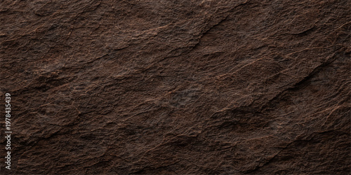 A rough dark brown stone texture background features a weathered rock surface with a dirty grunge pattern and gray macro structure for a textured material wallpaper