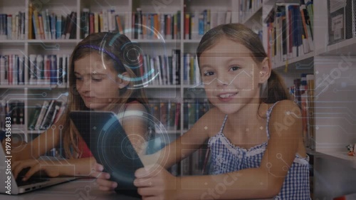 Two students typing on laptop and tapping tablet in library, tablet tap initiating HUD for learning