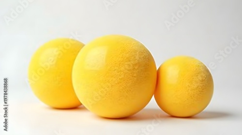 Three Smooth Yellow Spheres with Varying Sizes on a Bright White Background