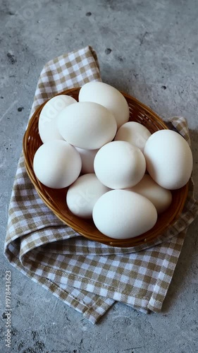 Fresh white eggs nestled in a rustic basket atop a charming checkered cloth in a cozy kitchen setting