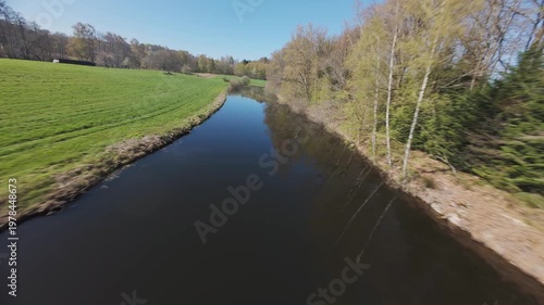 fpv drone flying over forest and pond with cloud relections and algae on a sunny spring day in Vosges region