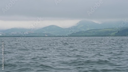 The city of Petropavlovsk-Kamchatsky and the waves of Avacha Bay in the Pacific Ocean in gloomy, cloudy, rainy weather.