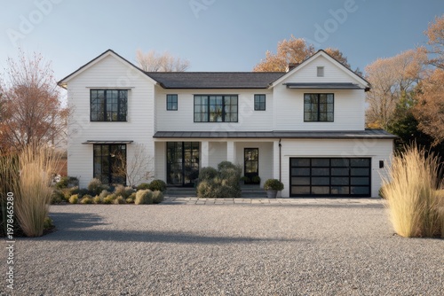 Modern house with a gravel driveway and landscaped yard in a suburban neighborhood during daytime with clear skies and trees in the background