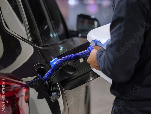 Filling diesel exhaust fluid in a car close-up. Refilling the AdBlue tank manually at a gas station in Germany. Chemicals based on an urea solution to reduce the exhaust emissions (nitrogen oxides).