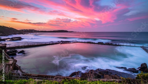 Waves crash against rocky shoreline at sunset over ocean