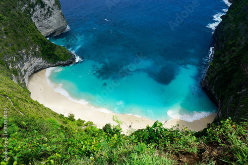 Top-down view of a secluded sandy beach surrounded by cliffs and turquoise water in Bali, ideal for travel marketing, tourism visuals, and tropical escape themes.