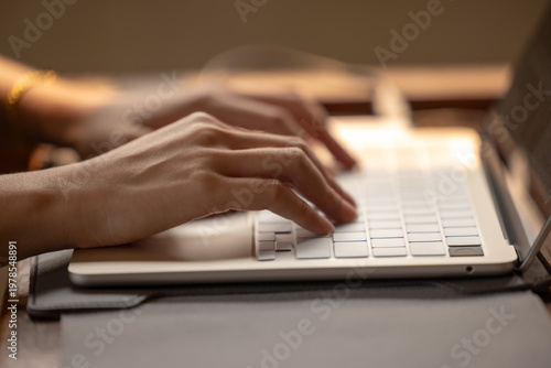 Hands typing on a laptop keyboard, focused on work in a modern setting.
